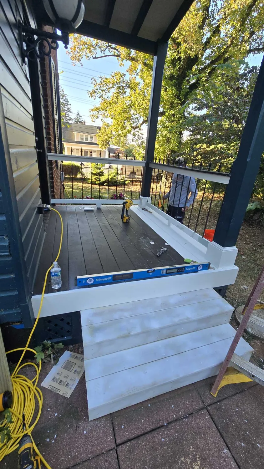 New white porch railing, balusters and front steps being levelled into place